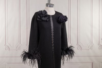 une photo d'un manteau noir orné de plumes, présenté sur un mannequin