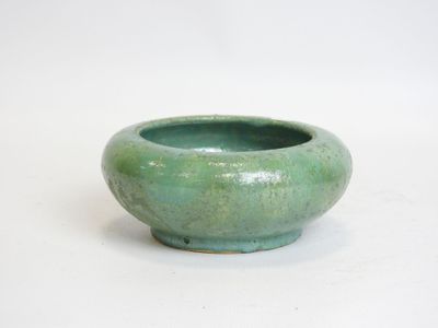 a green bowl that is sitting on a white surface