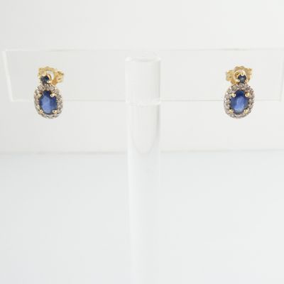 a pair of sapphire and diamond earrings on display in a glass holder