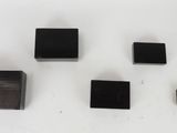 four black square magnets on a white surface with a white background