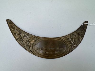 une vieille plaque en laiton sur laquelle est apposée une inscription, posée sur une surface blanche