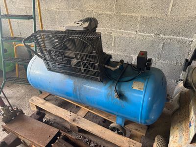 un compresseur d'air bleu posé sur une palette dans un garage