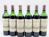 six bouteilles de vin sont alignées sur une surface blanche