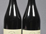 two bottles of red wine sitting next to each other on a table