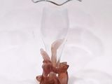 a glass vase with a bird on it on a white surface