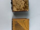 two old books are sitting on a white surface next to each other