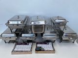 a lot of silver trays with lids on a table