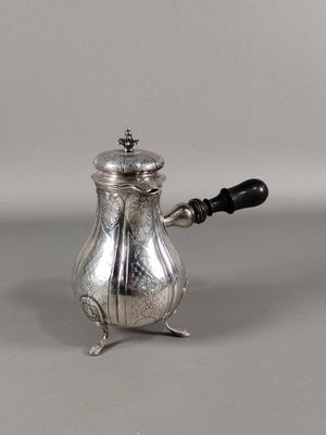 une cafetière ancienne en argent, avec une poignée noire sur un fond gris