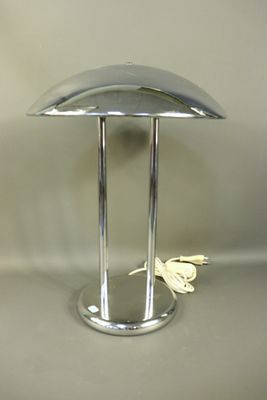 une lampe de table argentée sur laquelle est posé un papillon blanc