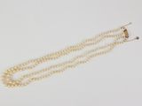 a close up of a white pearl necklace with a gold clasp