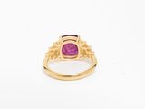 a close up of a gold ring with a pink stone