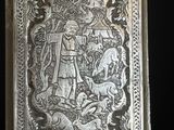 une vieille assiette en argent sur laquelle est représenté un homme et un chien