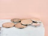 coins are sitting on top of a marble block on a pink background