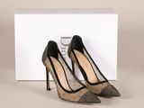 une paire de chaussures à talons hauts noires et argentées posées devant une boîte blanche