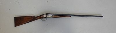 Le pistolet est accroché au mur, à côté du mur blanc.