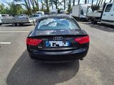 a black car parked in a parking lot with trees in the background