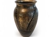 a brown vase with holes in it on a white surface