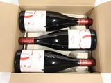 three bottles of red wine in a cardboard box on a white surface