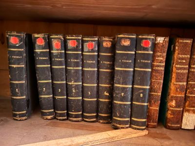 de nombreux livres anciens sur une étagère, à côté d'une batte de baseball