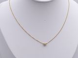 a gold necklace with a small diamond on a white mannequin