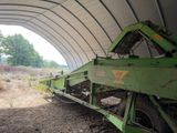 a green tractor parked under a large metal structure