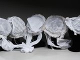 Plusieurs chapeaux sont alignés sur un présentoir noir pour mannequin