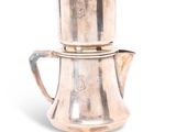 une cafetière en argent posée sur une théière en argent