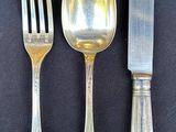three silver spoons and a knife on a black table