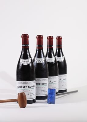 four bottles of wine and a wooden mallet on a white surface