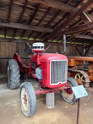un tracteur rouge dans une grange, avec une pancarte à l'avant