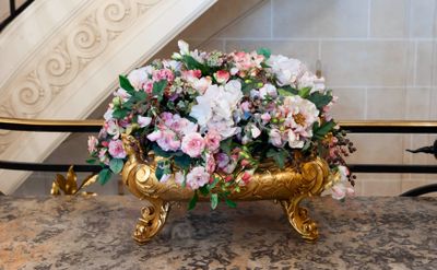 a gold vase with flowers in it on a marble table