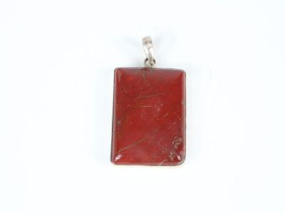 a close up of a red stone pendant on a white surface