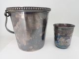 a silver bucket and a silver cup on a table