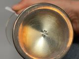 a person holding a silver cup with a handle