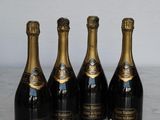 four bottles of champagne are lined up on a marble table