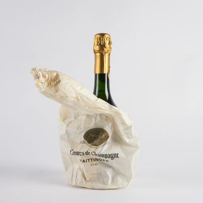 une bouteille de champagne dans un sac en papier, posée sur une table