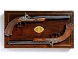 une vieille paire de pistolets dans un coffret en bois, sur fond blanc