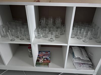 bottles and glasses on a shelf in a room with tile flooring