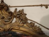 a mirror with a gold frame and a bird on top of it