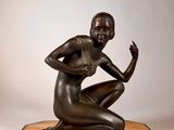 une image représentant une statue en bronze d'une femme assise sur un socle en marbre