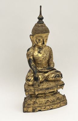 une statue en or représentant un Bouddha assis au sommet d'une pile de livres