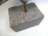 un parpaing d'où sort un marteau, posé sur une surface blanche
