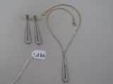 two silver necklaces and a pair of earrings on a white surface