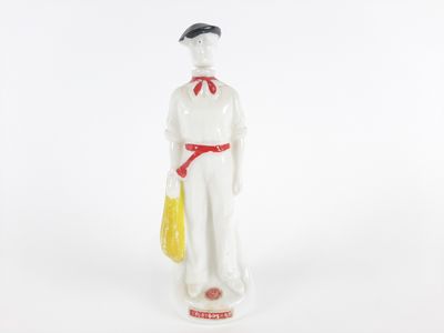 figurine représentant une femme en robe blanche avec un sac jaune