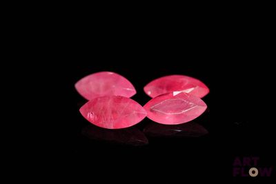 un gros plan sur deux pierres précieuses roses posées sur une surface noire