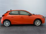 the orange car is parked in the parking lot near the wall