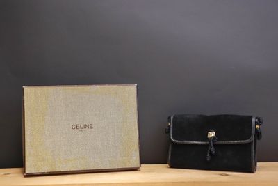 the black clutch bag is next to the box on the wooden table