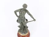 an antique bronze statue of a man with a bow on a wooden base
