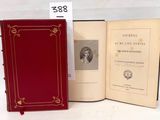 un livre ouvert posé sur une table blanche, à côté d'un livre rouge