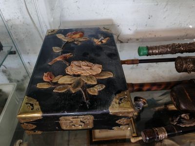 a black suitcase with gold flowers on it next to a pair of umbrellas